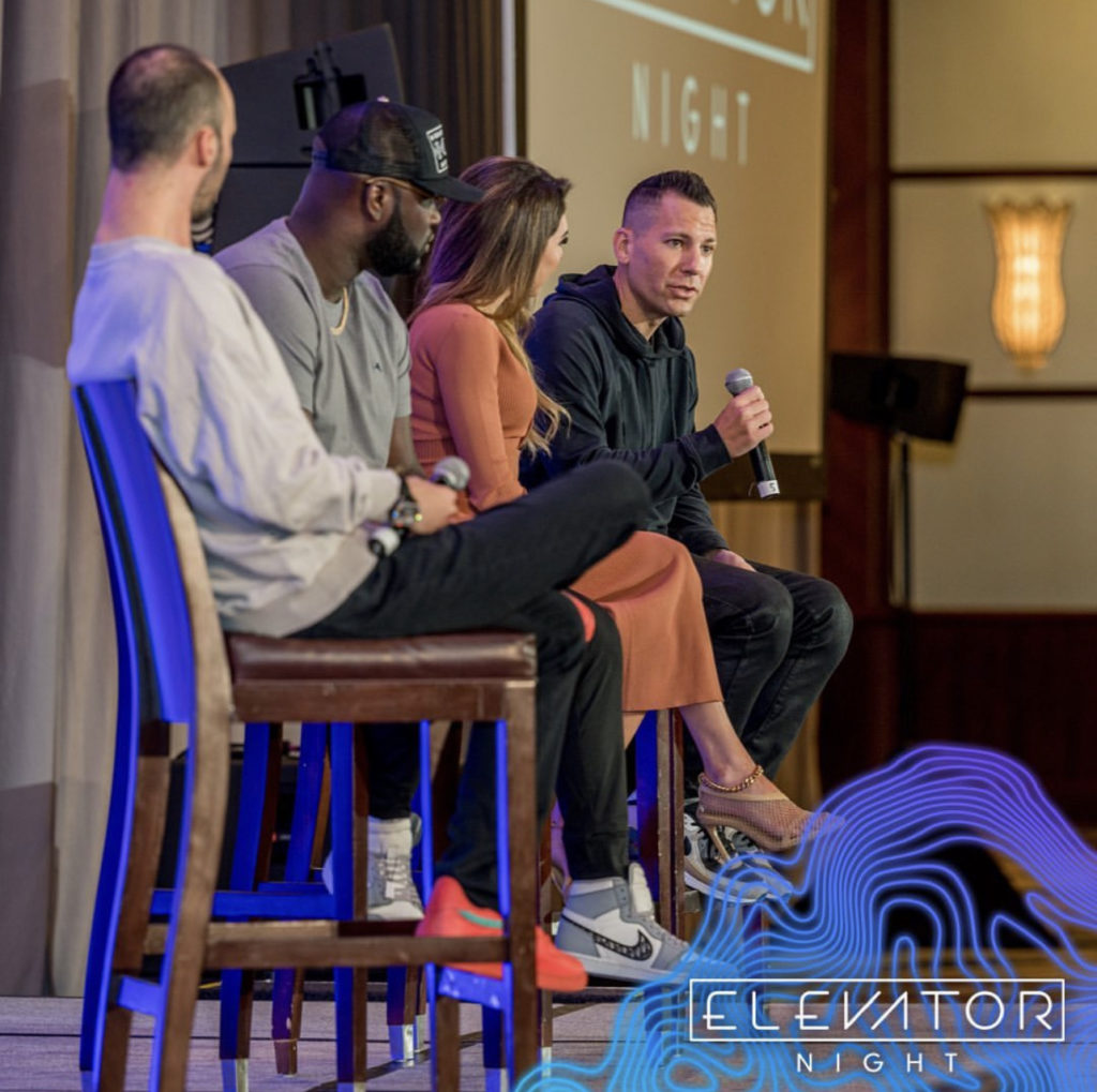 Elevator Night Miami Four people sit on stage for a panel discussion; one man speaks into a microphone. The event branding reads "Elevator Night.