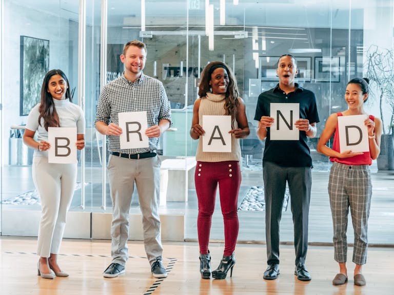 Happy Coworkers Holding up Letters on Pieces of Paper